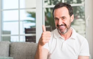 Handsome middle age man happy with big smile doing ok sign, thumb up with fingers, excellent sign