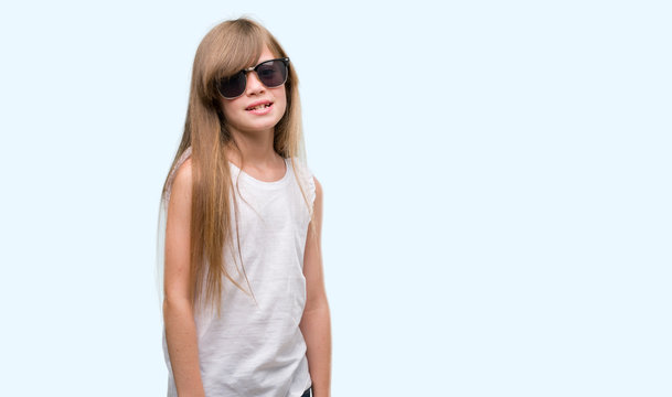 Young blonde toddler wearing sunglasses with a happy face standing and smiling with a confident smile showing teeth