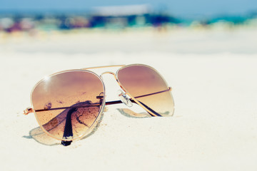 Vintage photo of nostalgia in summer - sunglasses on sand beach. retro film filter effect