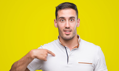 Handsome young casual man wearing white t-shirt with surprise face pointing finger to himself