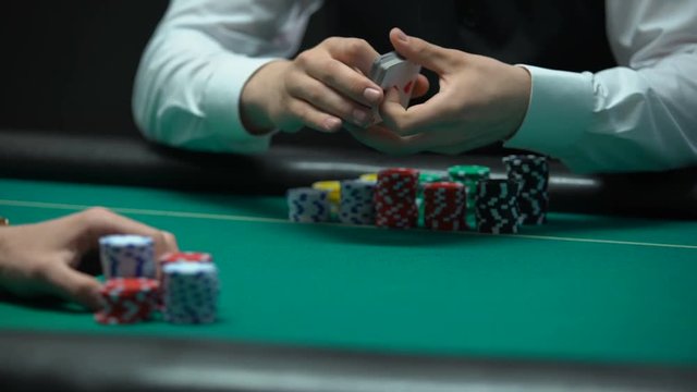 Croupier dealing cards on green table, poker player checking combination
