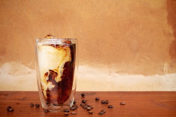 a glass of homemade cold cold brew coffee with milk on wooden table