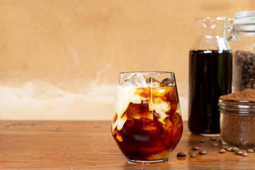 a glass of homemade cold cold brew coffee with milk on wooden table