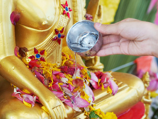 Fototapeta premium Close up hand watering to golden buddha statue