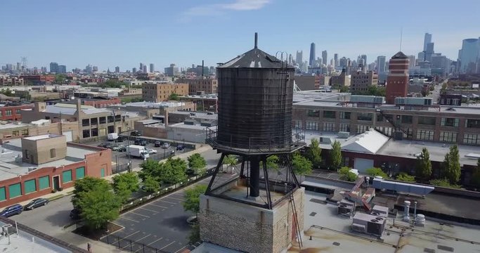 Clockwise Orbiting Drone Shot of Rooftop Water Tower in a Big City
