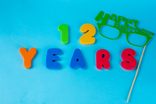 12 years old celebrating classic logo. Colored happy anniversary 12 th colored numbers on blue background. Greetings celebrates card. Traditional digits of ages. Flat lay .