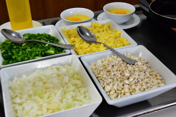 Finished, sliced ingredients for cooking a delicious breakfast. Omelette. Everything is spread out over cups of a good dining room. Onion, pepper, cheese, mushrooms