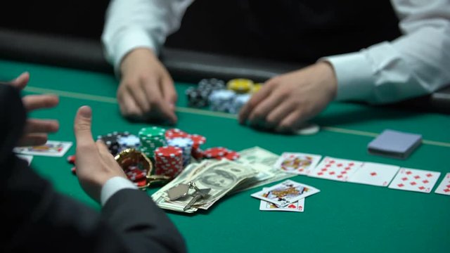 Sad casino player losing poker game, professional croupier taking all chips