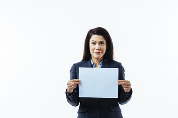 Naklejka premium Portrait of a pleasant woman in grey jacket holding blank sign, isolated on white studio background