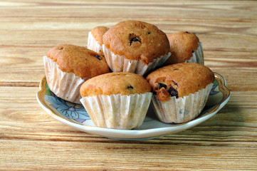 Fresh muffins on a plate on wooden background