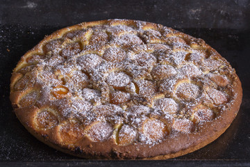 Homemade organic apricot pie dessert ready to eat . Apricot tart with walnut on black background