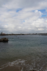 Coastline view from beach shore in Southern California with cityscape and sailing boats in the background. Summer vacations at the beach for relaxation tranquility and peacefulness