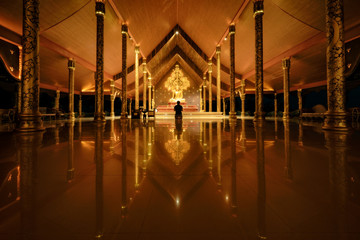 Young man traveler sitting and pray in church or chapel at Wat Sirindhorn Wararam Phu Prao temple or Wat Phu Prao is situated near the border between Thai and Laos at Ubon Ratchathani, Thailand.