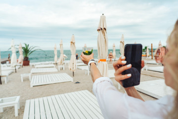 holding a phone and taking a picture of a cocktail