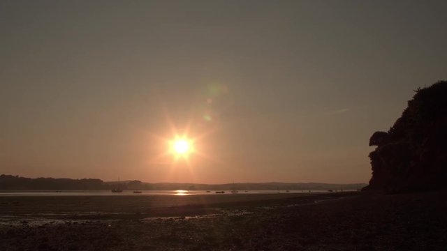 TIME LAPSE of sunset over the coastal town of Lympstone in England. Sun is slowly setting over the horizon. The glow is reflecting in the water.