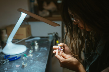 Fototapeta premium girl master processes the metal plate in the home workshop