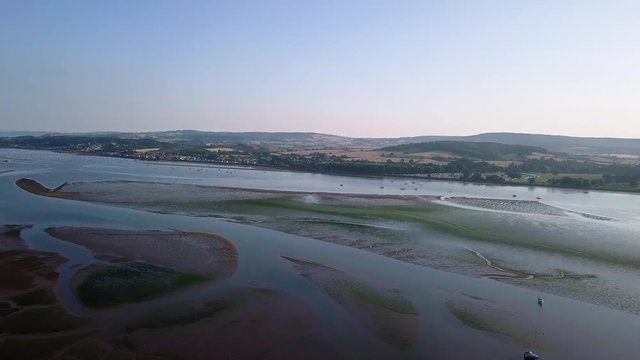 Flying over the ocean off of the shores of an historical town in southwest England. The water is calm, the landscape is beautiful, perfect as a vacation spot.
