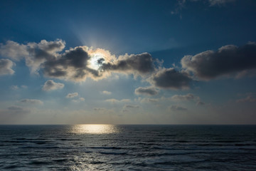 Obraz premium The Sun behind a cloud over the sea, horizontal