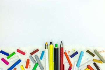school painting tools on paper sheet. colored crayons and markers on white background, flat lay