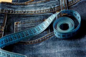 Blue jeans and a blue measuring tape close-up. Measurement of size. Diet and healthy.