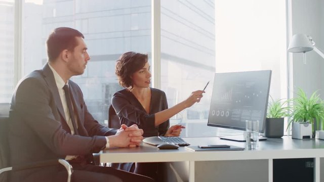 Female Top Manager and Male Businessman Sitting at the Desk Having Discussion and Working on a Desktop Computer, Solving Problems. 