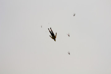 A group of skydivers is flocking in the sky.