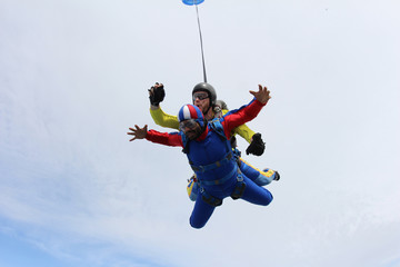 Fototapeta na wymiar Tandem skydiving. Indian man is in the sky.
