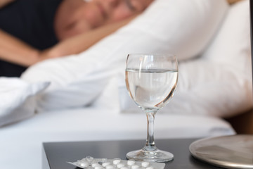 Glas Wasser vor einem Bett mit einer schlafenden Frau