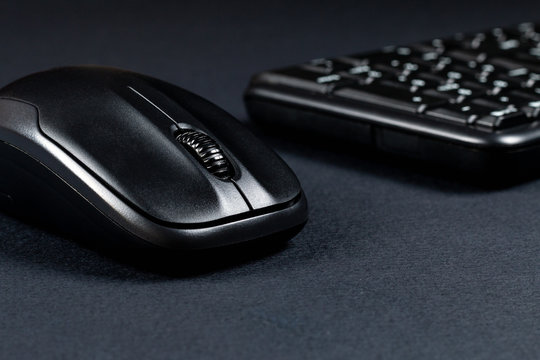 Wireless mouse with black keyboard on black surface