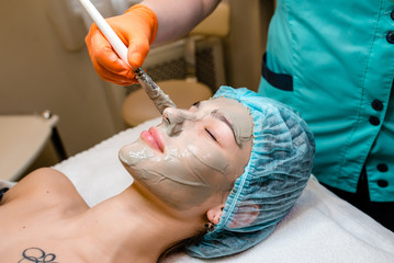 Beautiful natural girl woman in the spa salon, It makes a face mask, facial rejuvenation procedure, spa treatments.