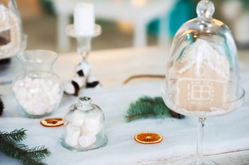 New year table setting. Gingerbread house and marshmallow in transparent glasses. Place, background
