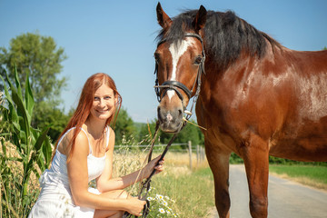 Fototapeta premium Rothaarige Frau Mädchen Model mit Pferd in der Natur im Sommer bei Sonnenschein
