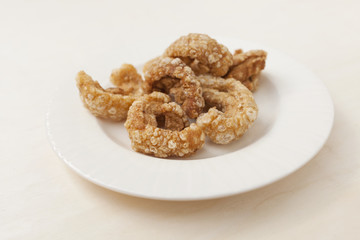 Closeup homemade pork rinds in ceramic plate, pork scratching or pork crackling, Thai style snack