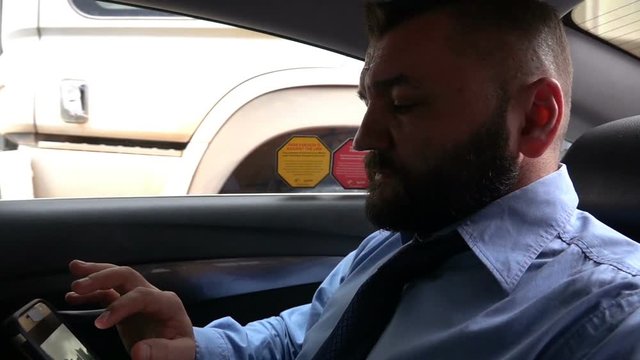 Young businessman texting smartphone during taxi ride, super slow motion
