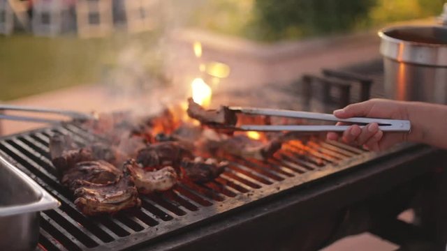 People barbecuing ribs over an open flame on a beautiful summer evening.