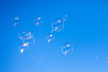 Soap bubbles in flight against the blue sky