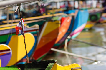 Phan Nga. Thailand. Colorful Thai longtail boats moored in the harbor waiting for tourists. On the rope attached to the flag of the country