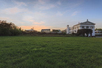 Moscow, Russia. Tsytsin Main Moscow Botanical Garden of Academy of Sciences. The building and greenhouse in the park at sunset. Green lawn in the foreground