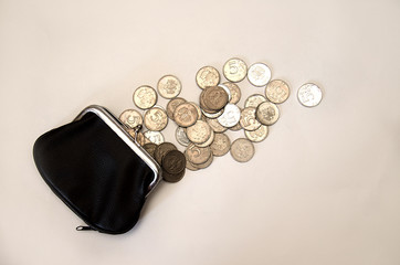 metal coins scattered next to a black purse, isolate on a white background