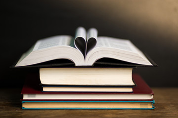 Book page in heart shape with dark background. Conceptual Heart from Book. Copy Space