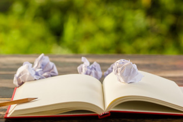 Concept no idea to creative thinking: Crumpled paper and note book on table with green nature background. Business concept plan thinking. Can not create idea for business or work plan. No inspiration.