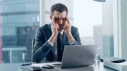 Stressed Out Businessman Sitting at His Desk, Massages His Head in Frustration. Overworked Businesspeople In the Window Big City Business District View. 