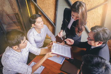 Businessman signing a contract during a meeting with business partners applauded.
