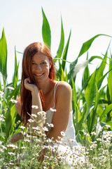 Rothaarige Frau Mädchen Modell sitzt in Blumenwiese in der Natur bei Sonnenschein im Sommer