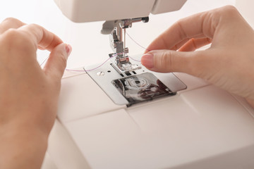 Female tailor threading sewing machine, closeup