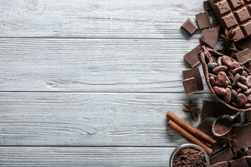 Composition with tasty milk chocolate, cocoa products and spices on wooden background