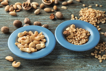 Plates with different nuts on wooden background
