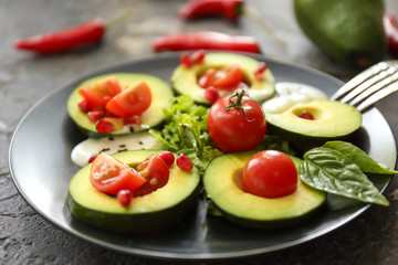 Ripe avocado, tomatoes and herbs on plate, closeup