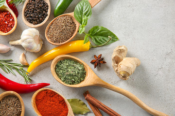 Wooden spoons with different spices on grey background
