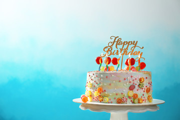 Stand with beautiful tasty birthday cake on color background